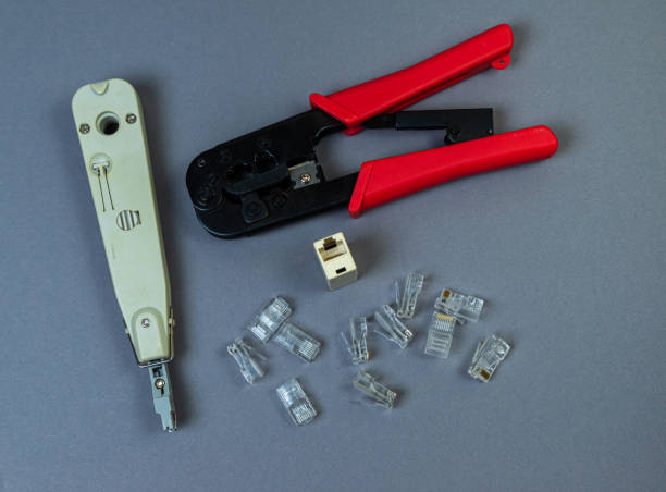 Hand crimp tool for crimping of the round terminals and small heap of blue insulated terminals on a white background