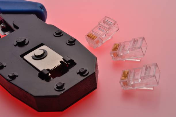 A rg45 connector for an internet cable and a twisted pair crimper lie on a multi-colored background. Close-up