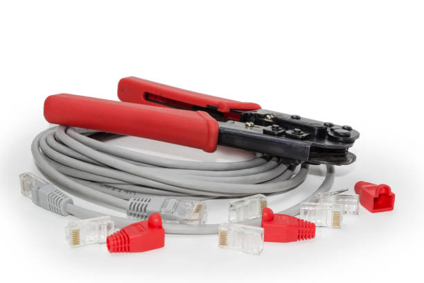 Modular crimper tool and some networking components for twisted pair on a white background, close-up in selective focus